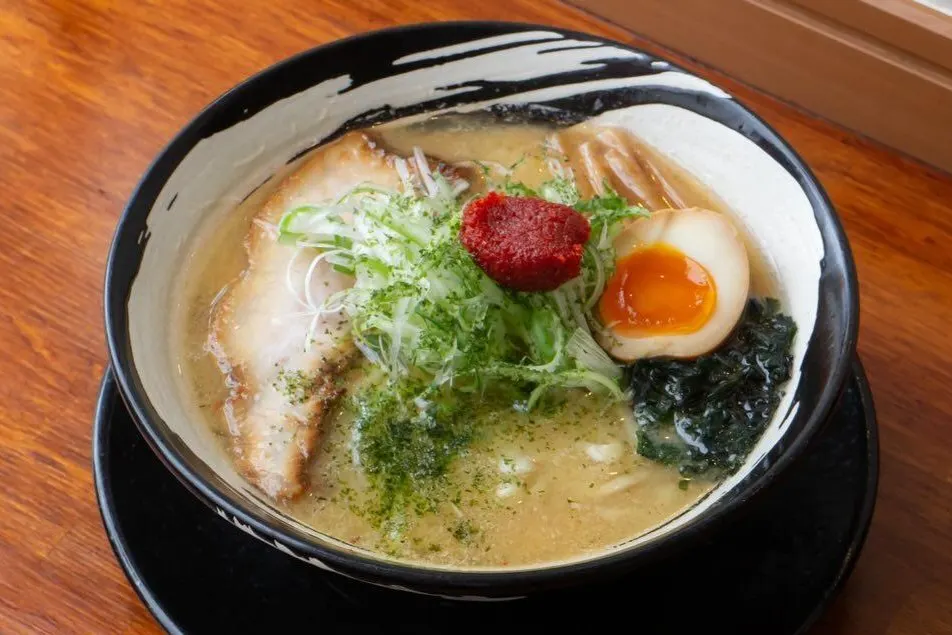 辛味噌らーめん。白黒の丼に味玉と青ねぎ、上に辛味噌がのっている