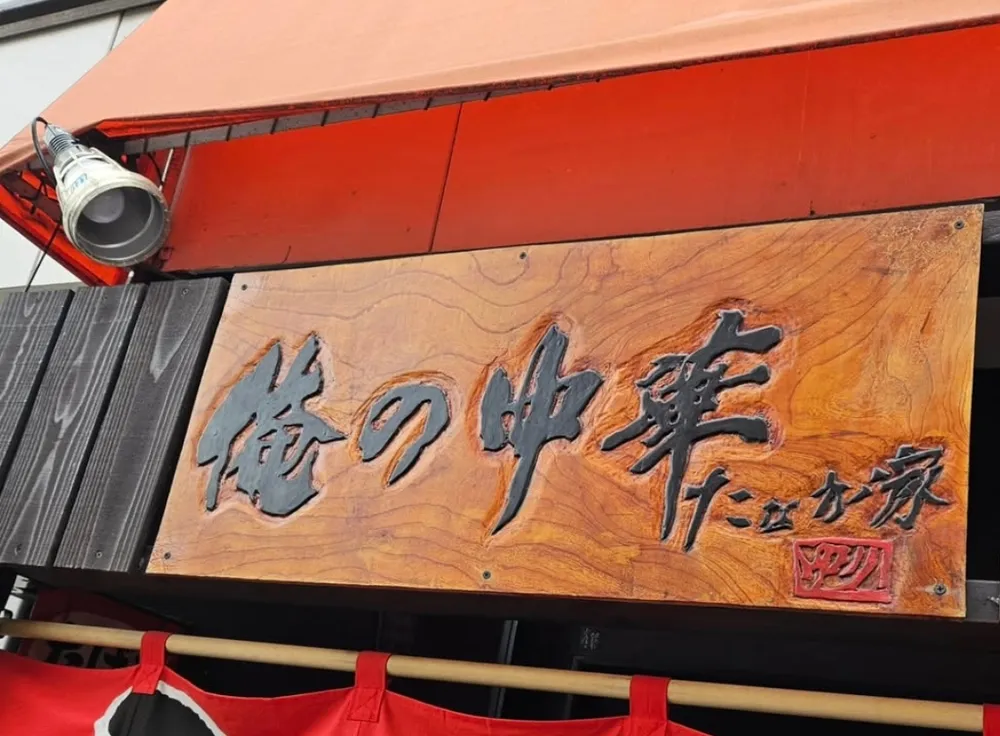 入口の上の木の看板と赤いのれん